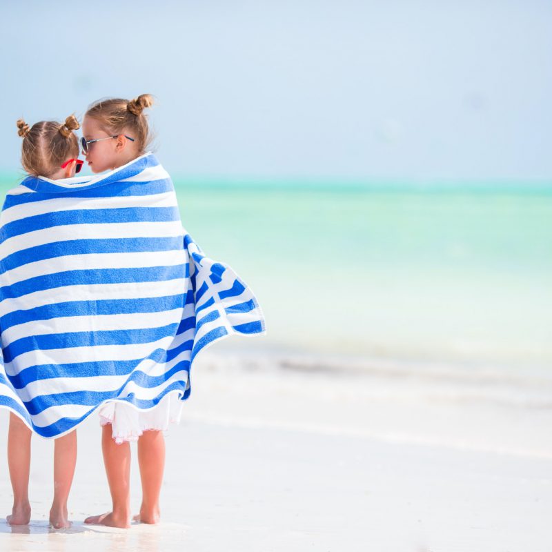 Little cute girls wrapped in towel at tropical beach. Kids on the beach vacation